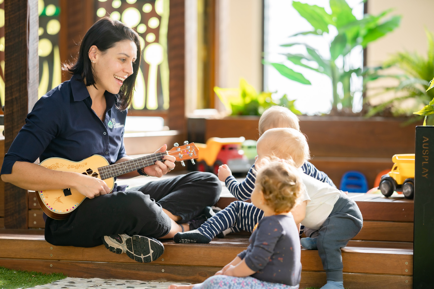 Teacher playing guitar to a group of children