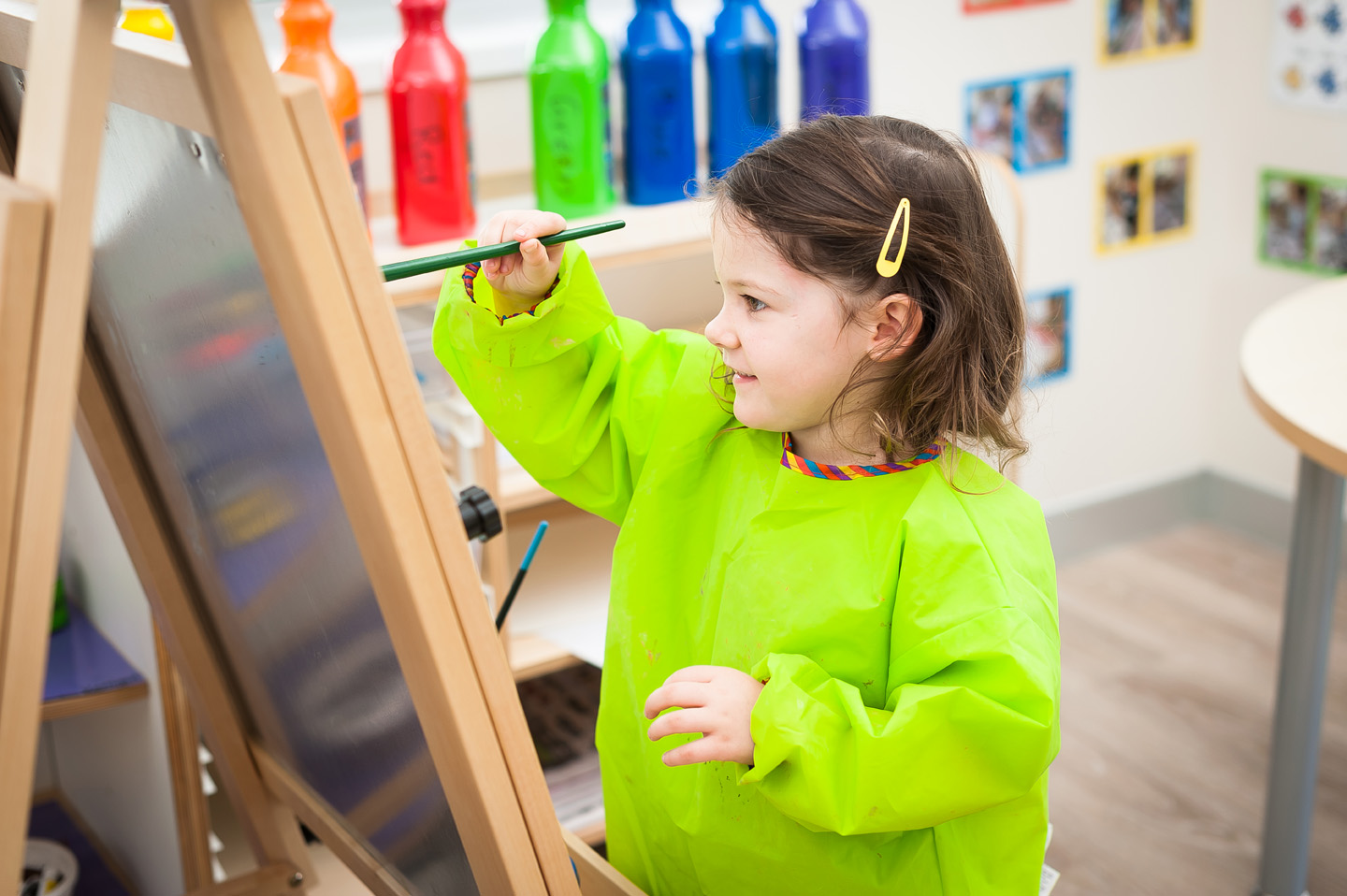Young child painting in bright green smock at Edge Early Learning Strathpine