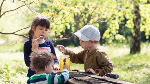 three children eating honey at a park