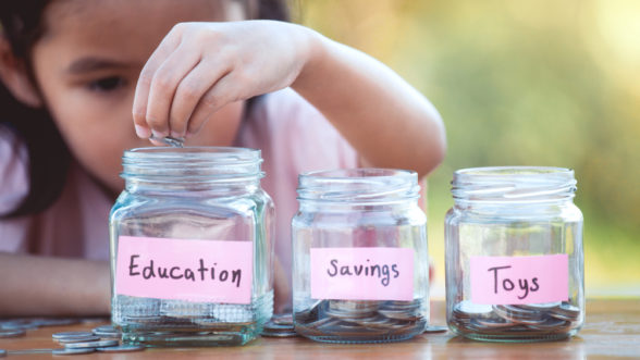 girl putting money into savings jars